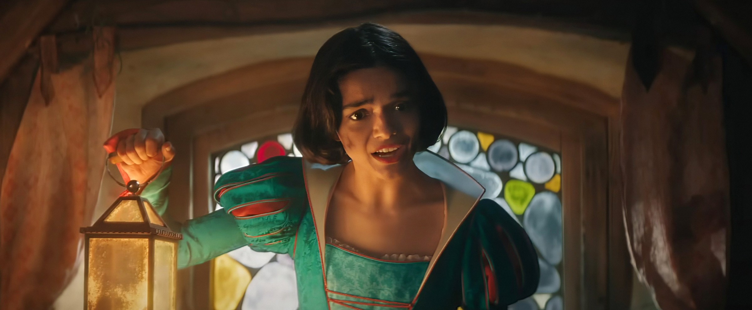 Snow White (Rachel Zegler) looks mussed, grubby, and deeply pained as she holds up a lantern in the dwarves’ house in the 2025 live-action Snow White
